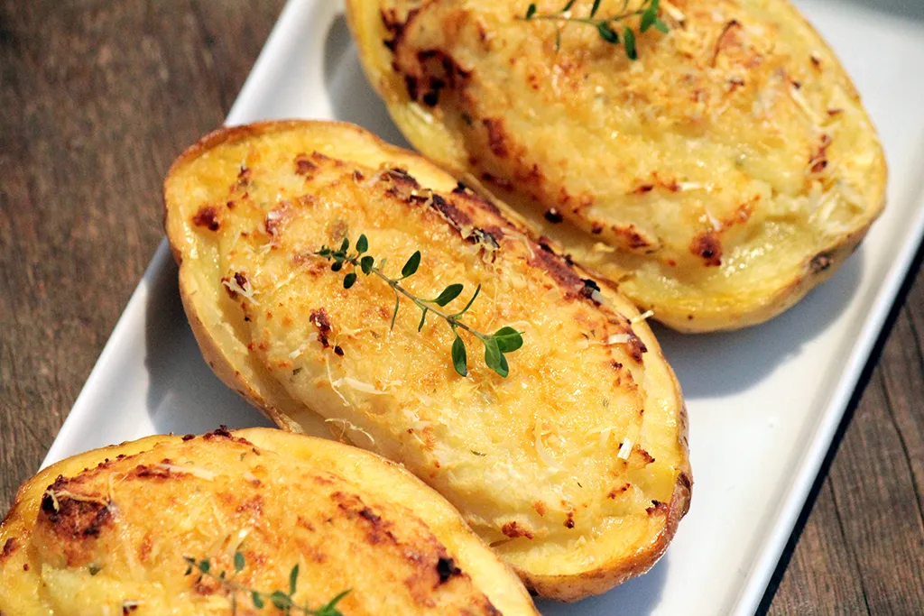 Batata recheada com alho assado e iogurte - Uma receita fácil, leve e simplesmente deliciosa. Essa batata tem um recheio feito com um purê de batata, pasta de alho assado, iogurte, queijo parmesão e tomilho. Depois é só colocar no forno para gratinar.