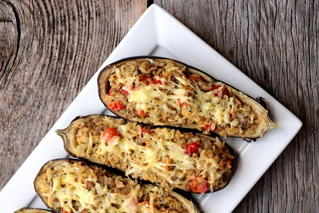 Berinjela recheada com arroz - Uma receita vegetariana, fácil e simplesmente deliciosa para você fazer em casa. Feita com berinjela, sobras de arroz, tomate, temperos e iogurte, essa berinjela recheada vai surpreender você.